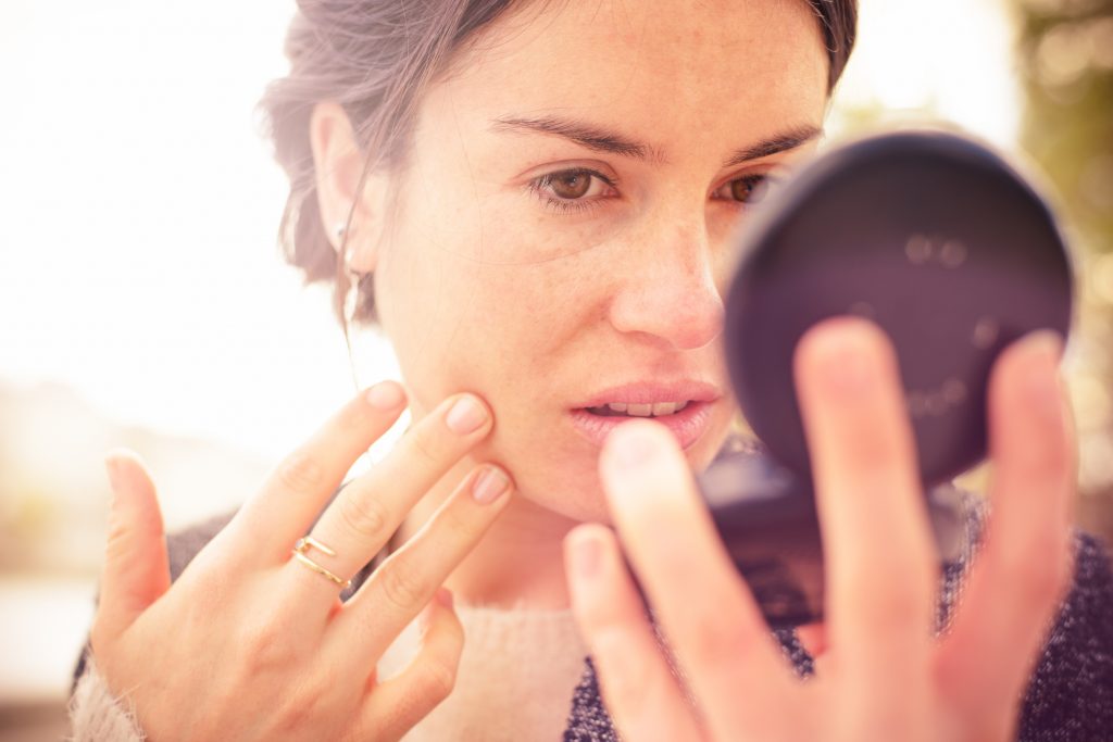 Woman checking appearance in compact mirror