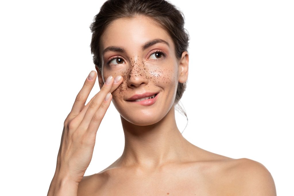 Young woman applying exfoliating scrub to her face